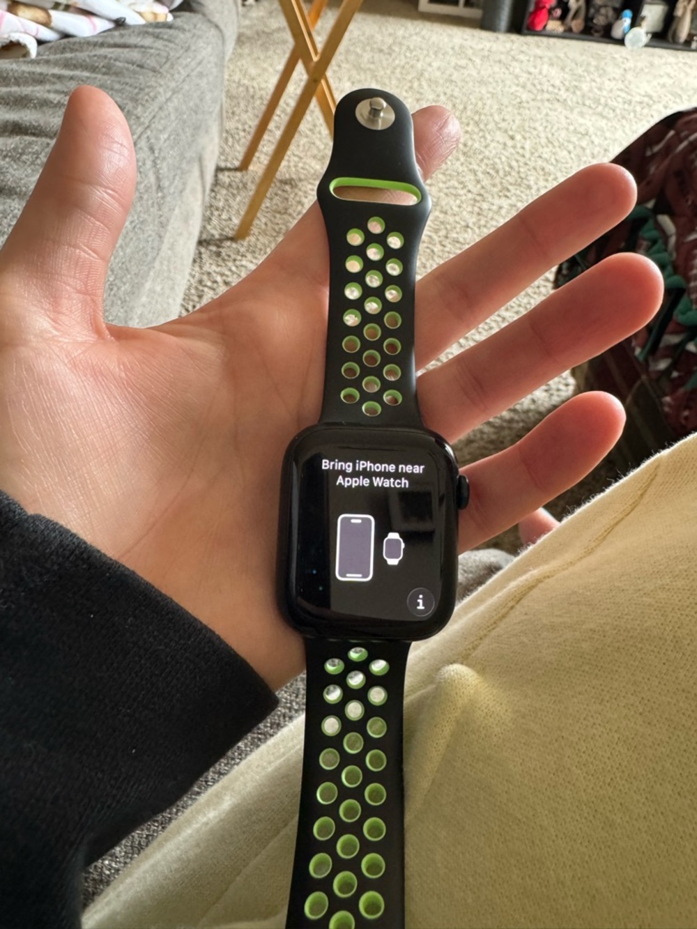 Apple Watch with a NikBlack and Lime Sport Band, charger, and the original band.